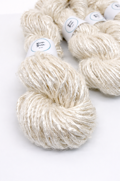 A skein of cream-colored yarn with labels on a white background