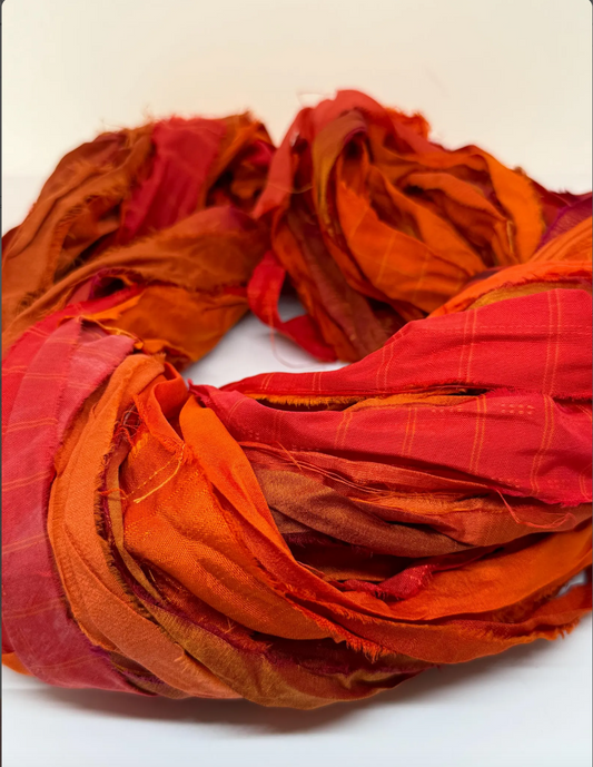 Sari silk ribbon yarn in sanguine orange for fibre arts and crafts.